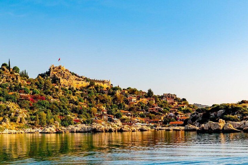A coastal town with a prominent hilltop fortress, calm water, and lush greenery. 4