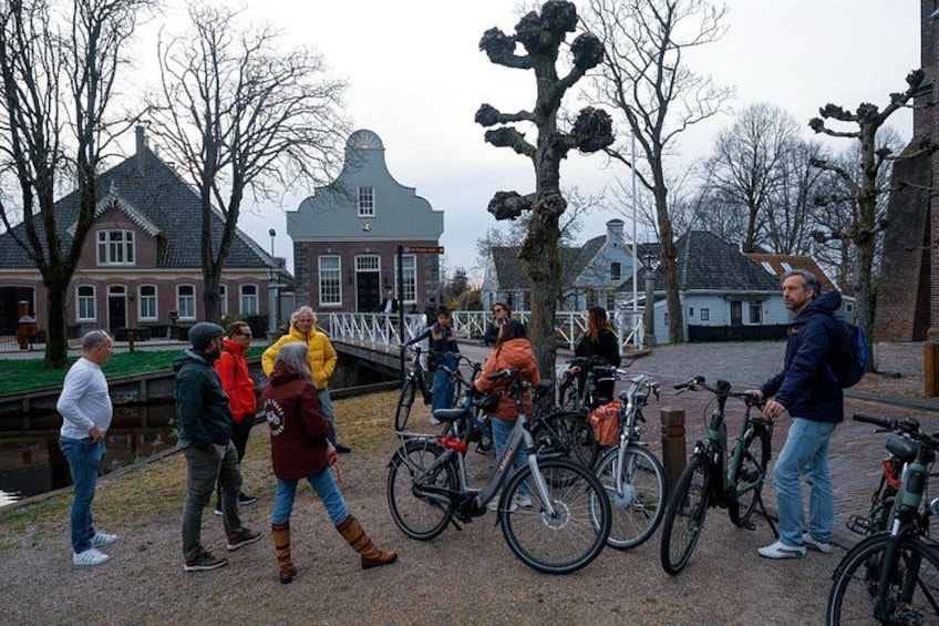 Un groupe de personnes se tient près de vélos, d’un canal et de bâtiments traditionnels. 2