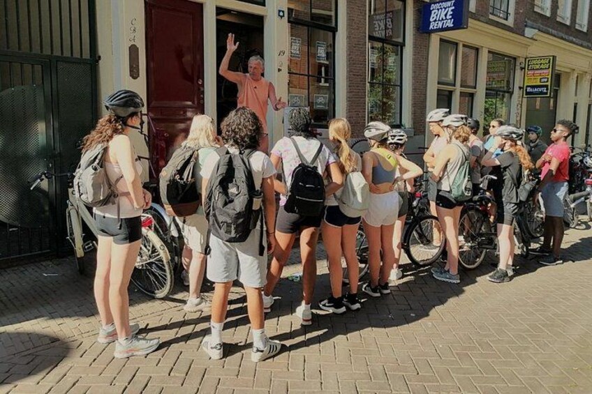 Un grupo de personas con bicicletas y cascos de pie frente a un edificio. 3