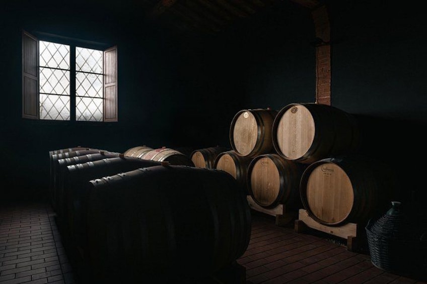 Barricas de madera apiladas en una habitación poco iluminada con una ventana. 3