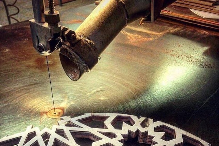 A machine cutting a metal sheet with a geometric pattern. 1