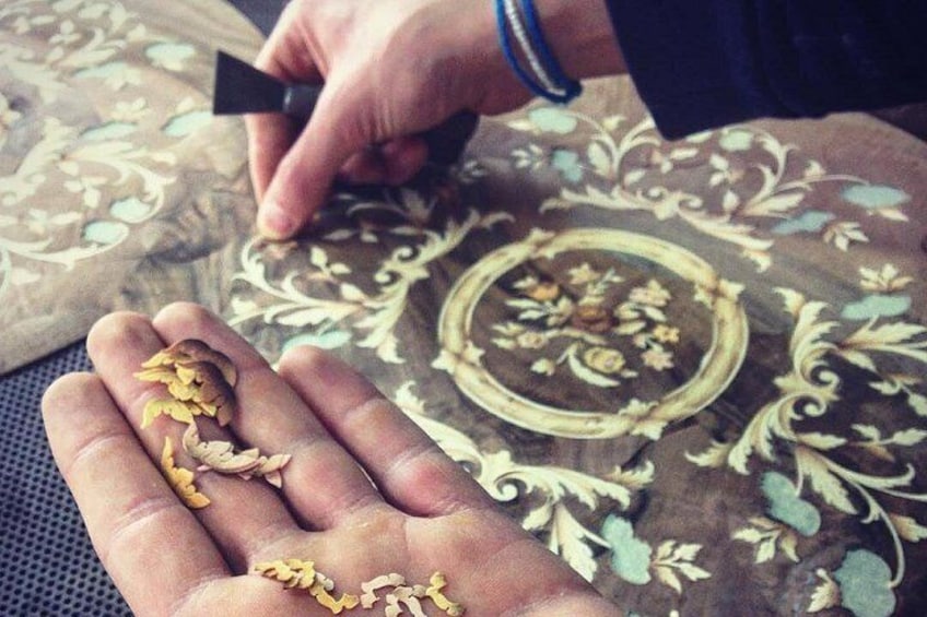 A hand holding small yellow objects, possibly seeds or grains, on a patterned fabric background. 5