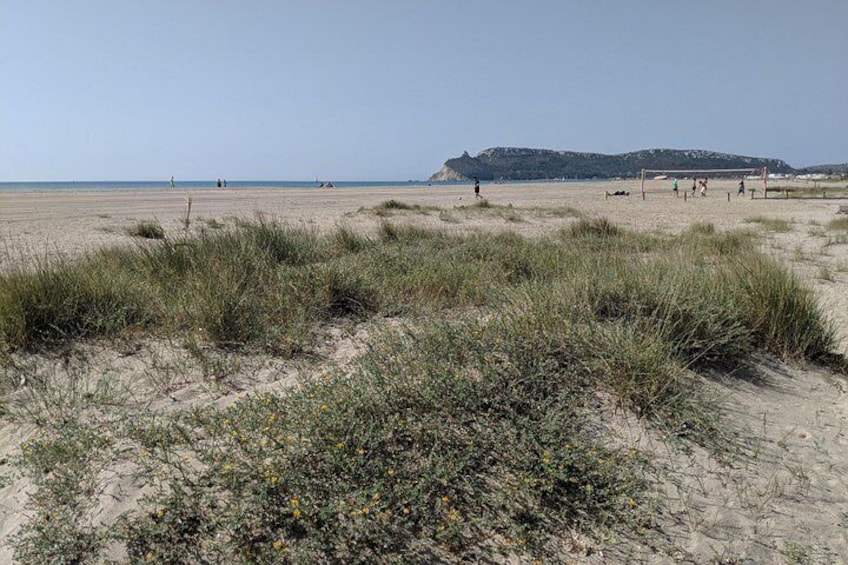 En strand med mennesker, der spiller fodbold, sandklitter og en fjern bakke. 3