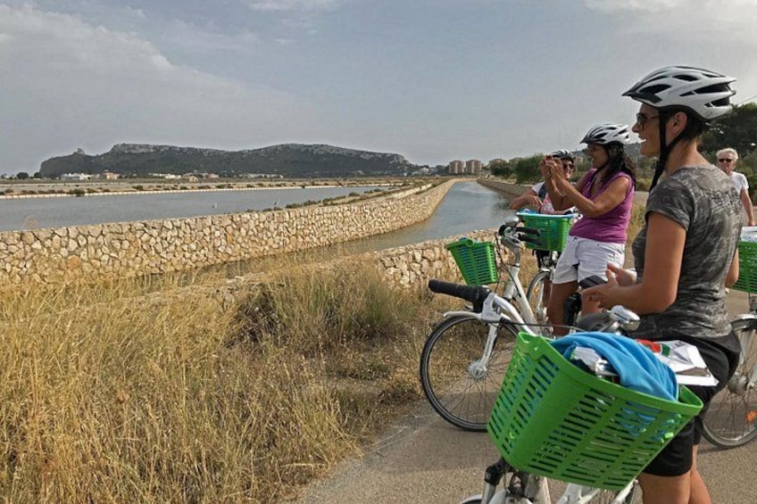 A group of people on bicycles along a riverside path with stone walls and greenery. 4