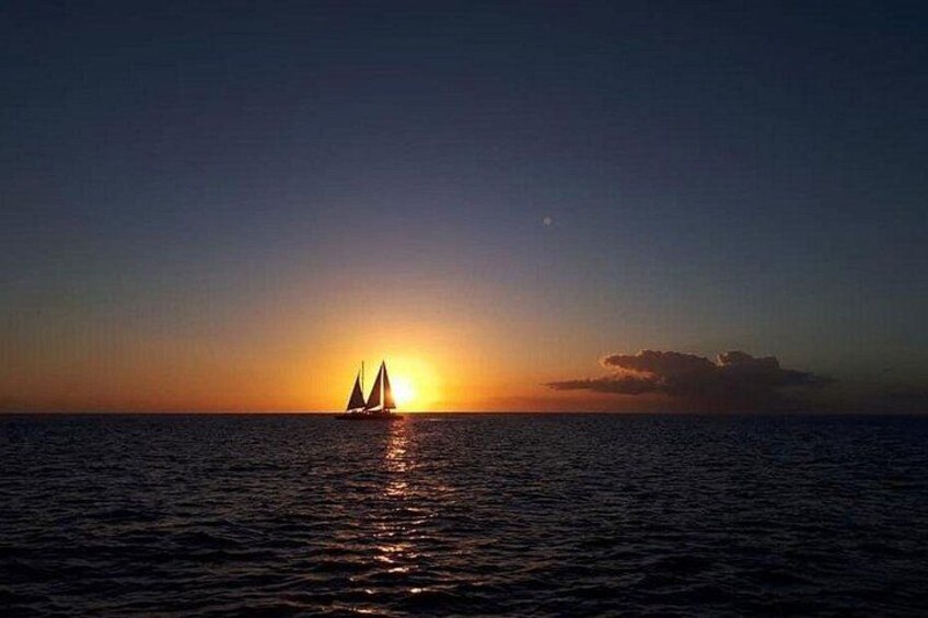 A sunset over a calm sea with a sailboat. 4