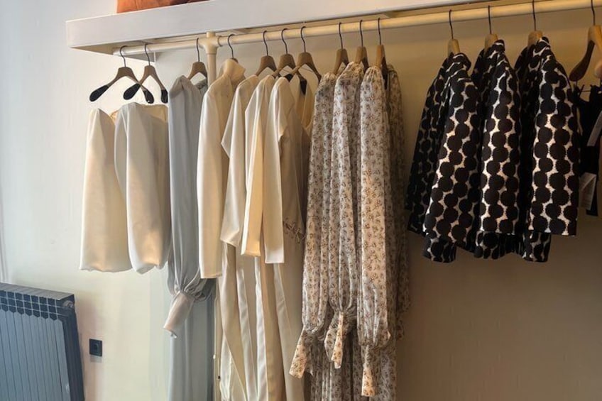 Un perchero con varias prendas de vestir, incluyendo blusas de colores claros y vestidos estampados. 4