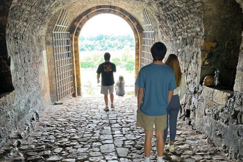 Ein steinbelagter Weg führt durch einen Rundbogen in einem historischen Gebäude. 3