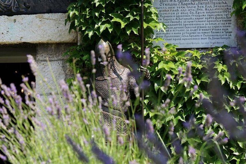 En statue delvist skjult af løv og et skilt med tekst. 2