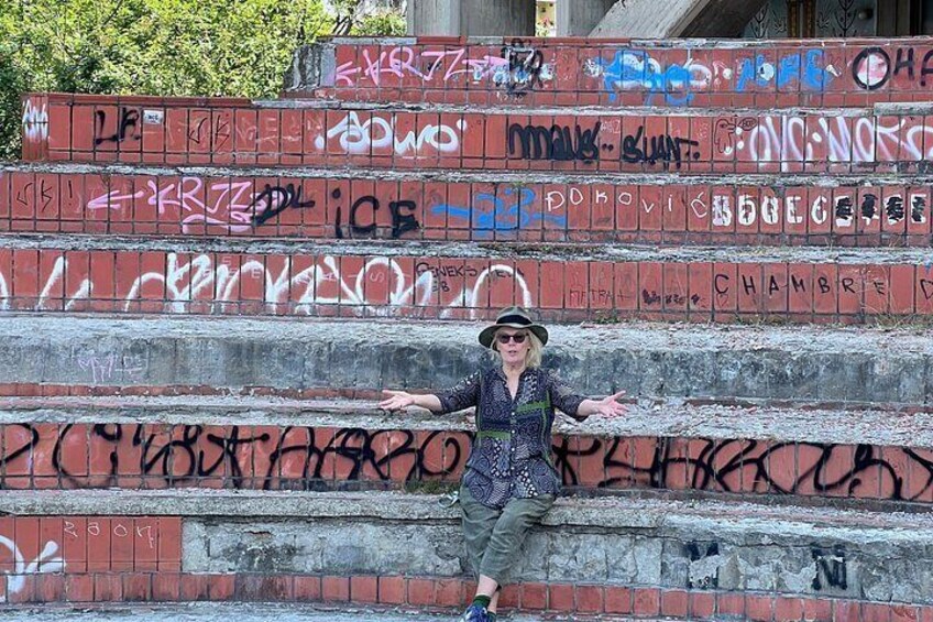 A person sitting on a graffiti-covered staircase. 5