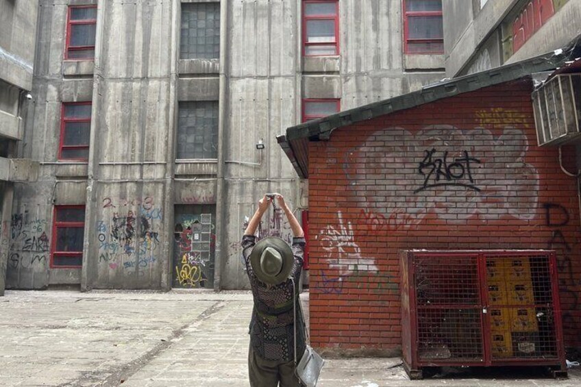 En person i taktisk udstyr står i en bygningsefterladelse med graffiti-dækkede vægge og en rød dør. 2