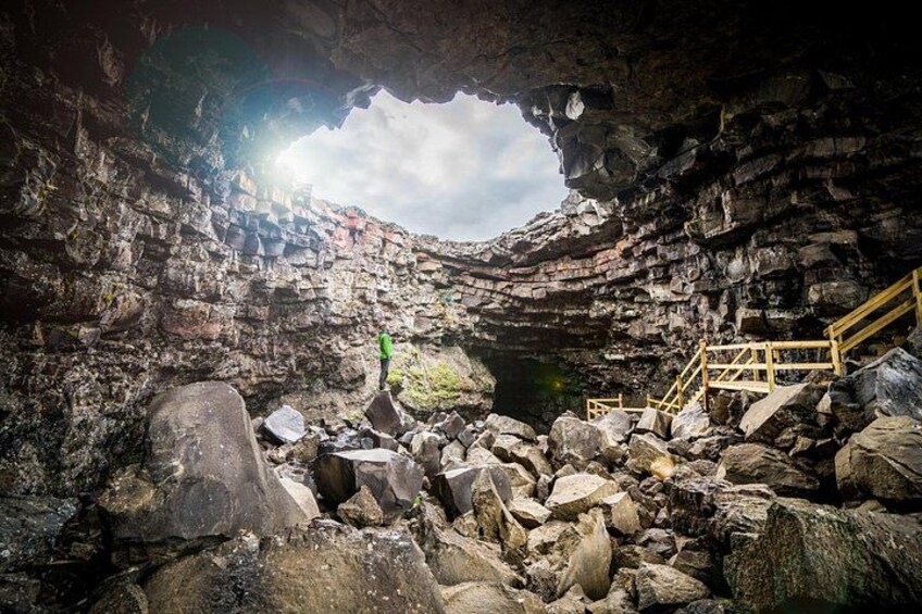 A cave entrance with a wooden staircase leading down. 1