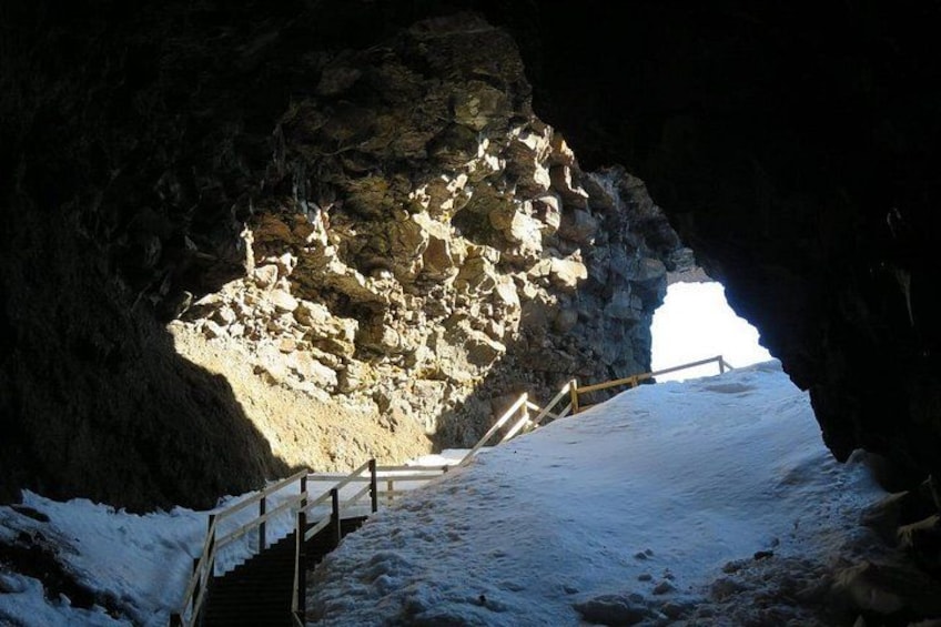 A snow-covered path leading into a rocky cave entrance. 3