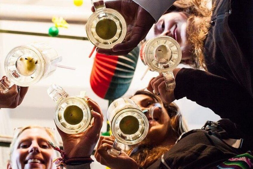 People holding glasses with a yellow liquid, possibly a drink, in a social setting. 2