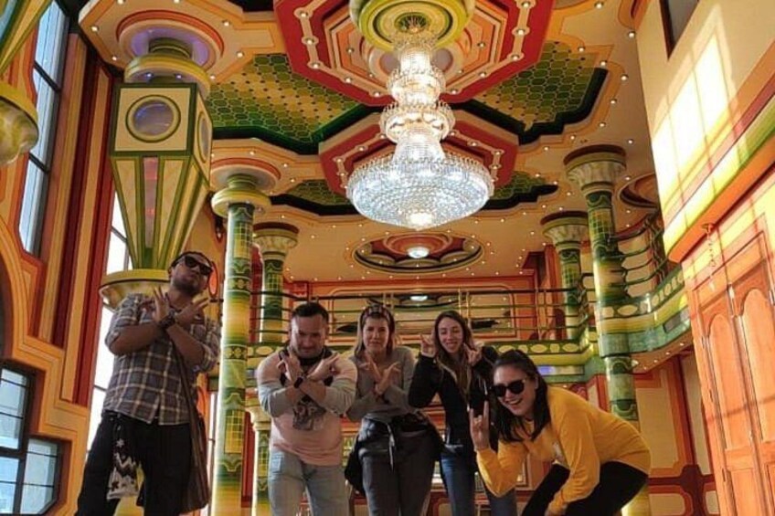 A group of people in a brightly colored room with ornate columns and a chandelier. 1