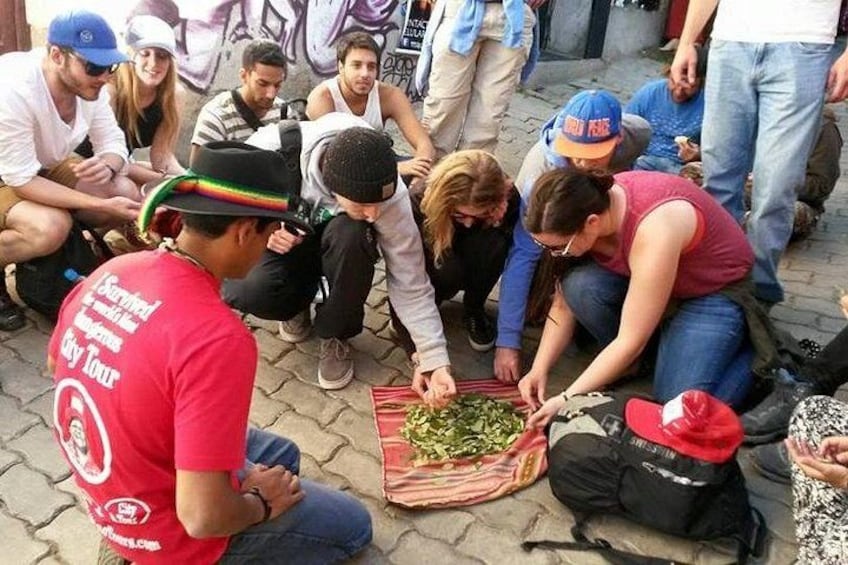 A group of people gathered around a table with a basket of green vegetables. 4