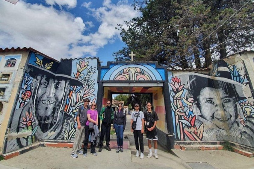 A group of people standing in front of a building with colorful murals. 2