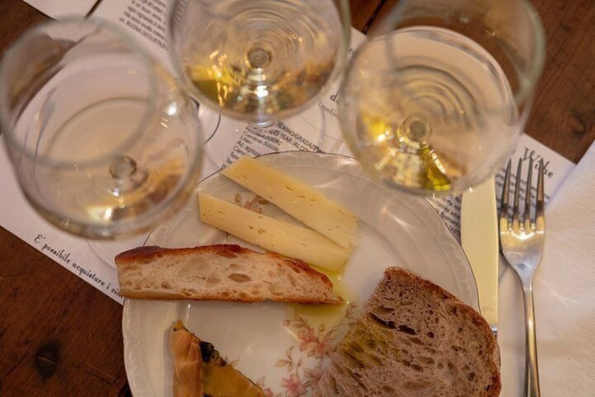Une assiette avec du fromage et du pain, trois verres à vin vides, une fourchette et un couteau sur une table. 2