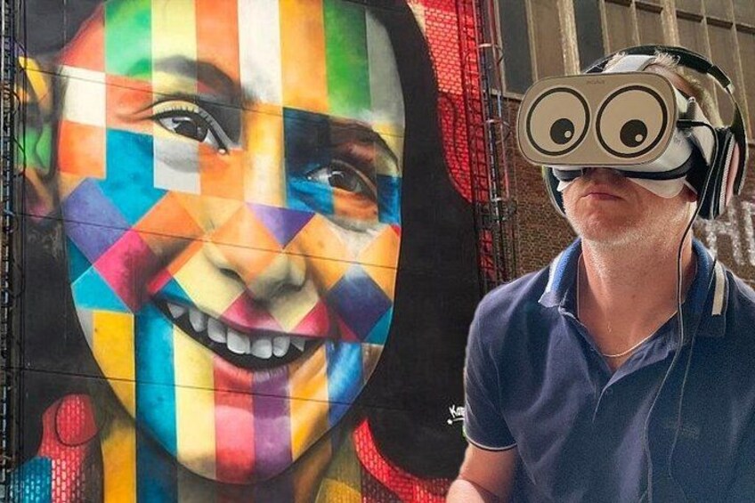 En person som bär ett VR-headset framför en färgglad väggmålning. 1
