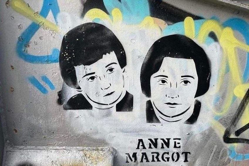 A graffiti wall with two portraits and the name 'ANNE MARGOT' below them. 4