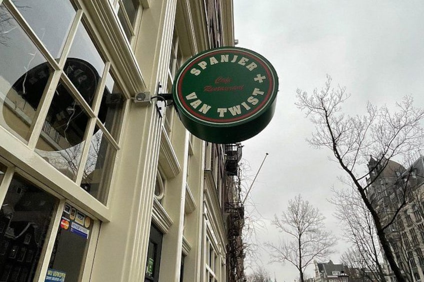 En grön skylt med texten ”SPANJER TWIST” på en byggnad. 5