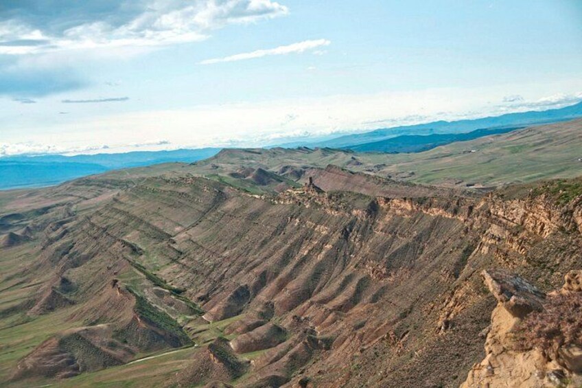 A rugged mountainous landscape with terraced fields and a distant body of water. 5