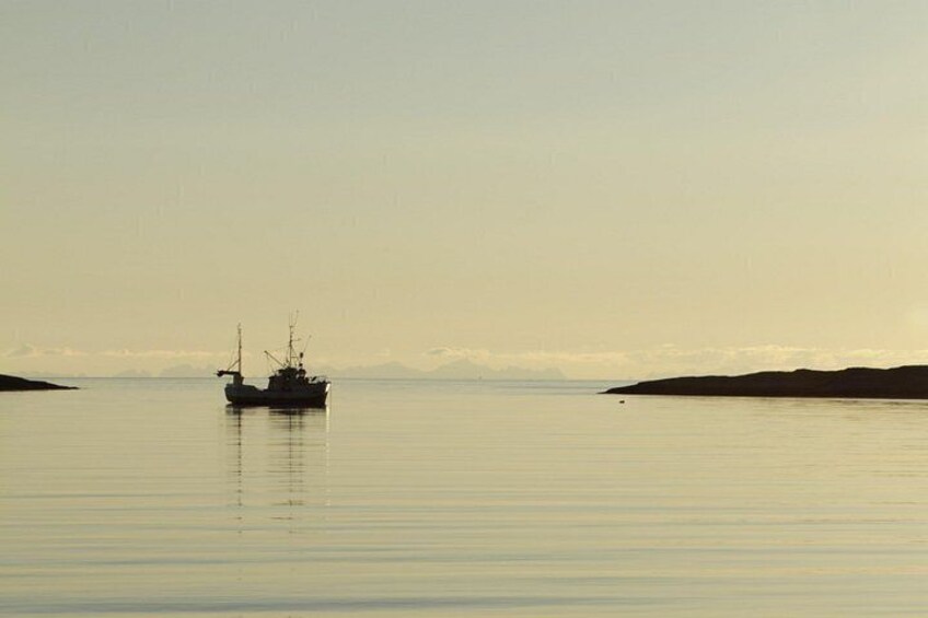 A calm body of water with a fishing boat in the center. 2