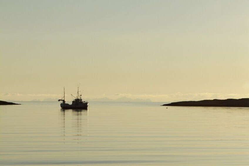 A calm sea with a fishing boat in the distance. 2