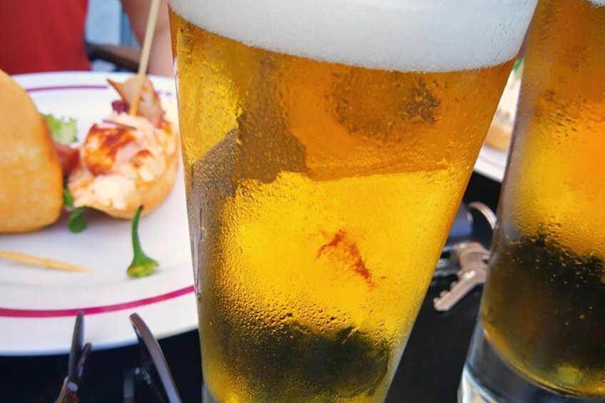 Un verre de bière avec une mousse onctueuse, une assiette de nourriture et une fourchette. 4