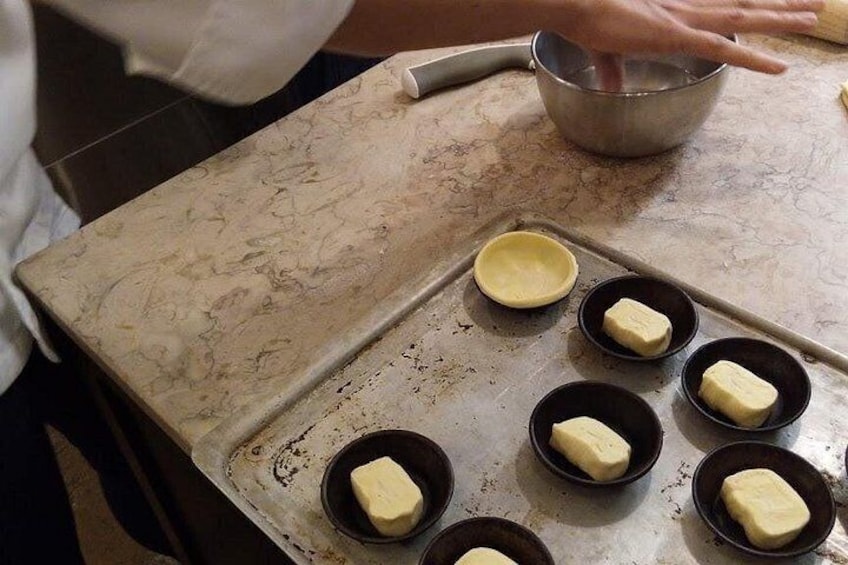 A kitchen counter with a baking tray containing several small bowls with butter. 1
