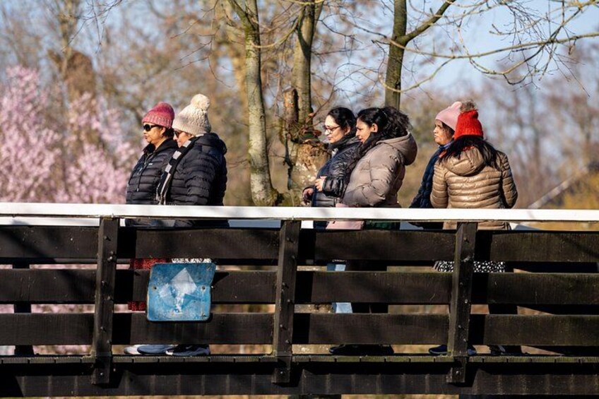Un groupe de personnes se tient sur un pont, avec des arbres et un panneau dans l’arrière-plan. 5