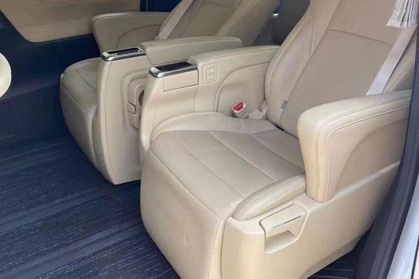 A car interior with beige leather seats, a center console, and a rearview mirror. 2