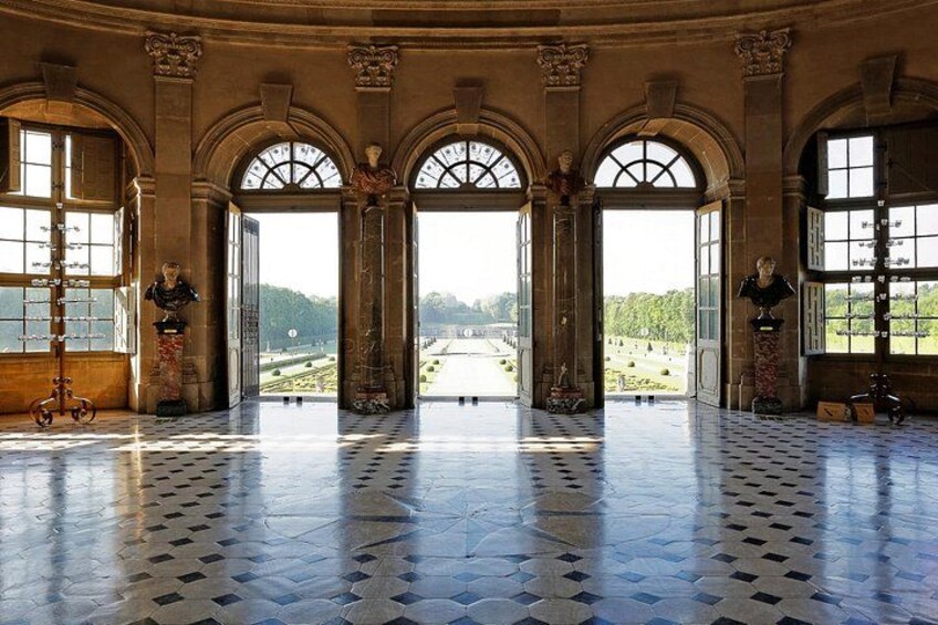A grand hall with arched windows, a tiled floor, and statues. 5