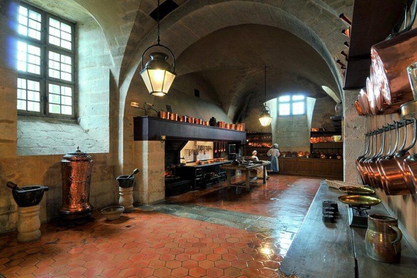 A historic kitchen with arched ceilings, copper pots, and brick flooring. 3