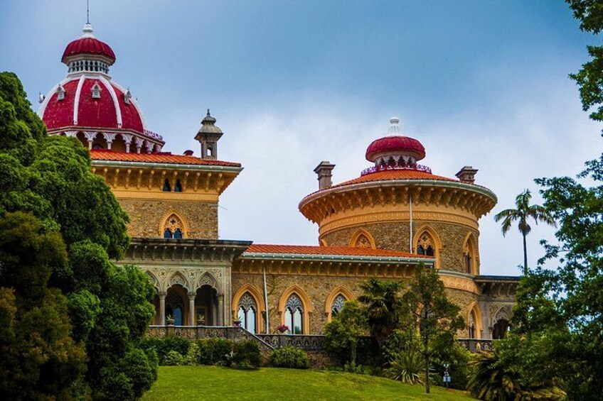 A large, ornate building with two prominent domes, one red and one yellow, surrounded by lush greenery. 2