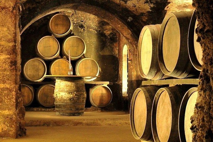 Wooden barrels stacked in an underground cellar with stone walls. 3