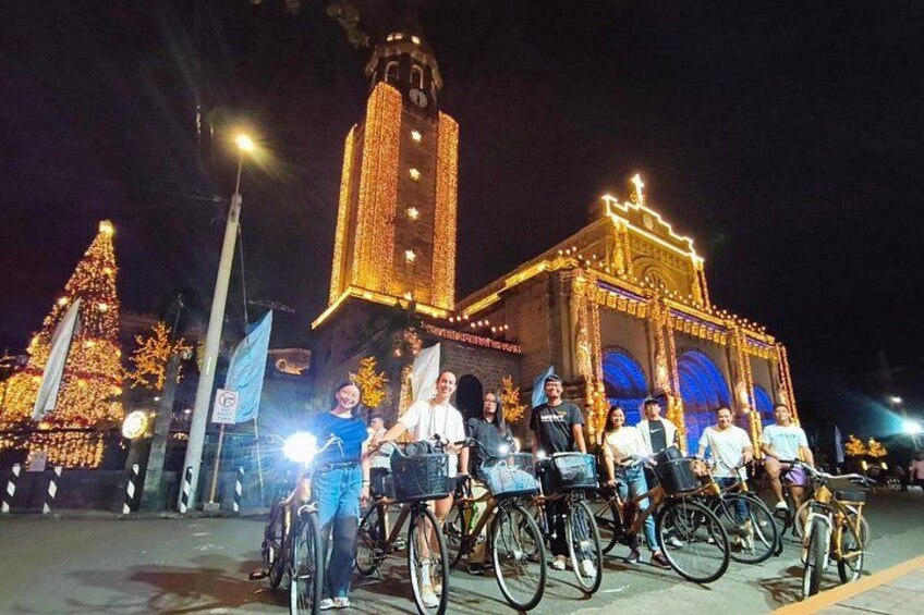 Un grupo de personas en bicicleta frente a un edificio iluminado con una torre de reloj. 5
