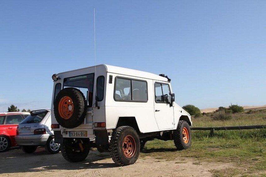 Un véhicule tout-terrain blanc, avec des roues orange, est garé sur un chemin de terre. 5
