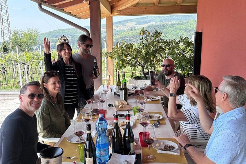 A group of people dining outdoors at a table with wine bottles and glasses. 5