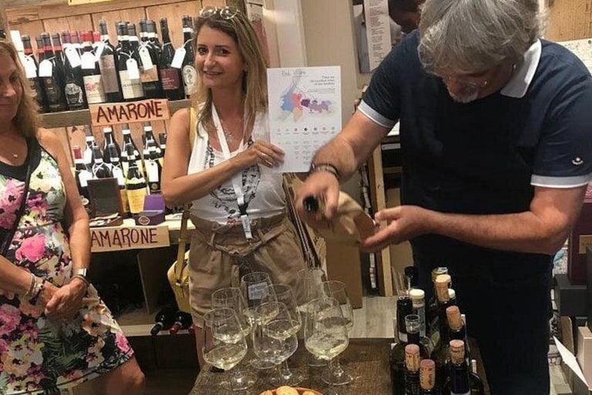 A person pouring a drink into glasses, a wine rack in the background, and a sign that reads 'AMARONE'. 4