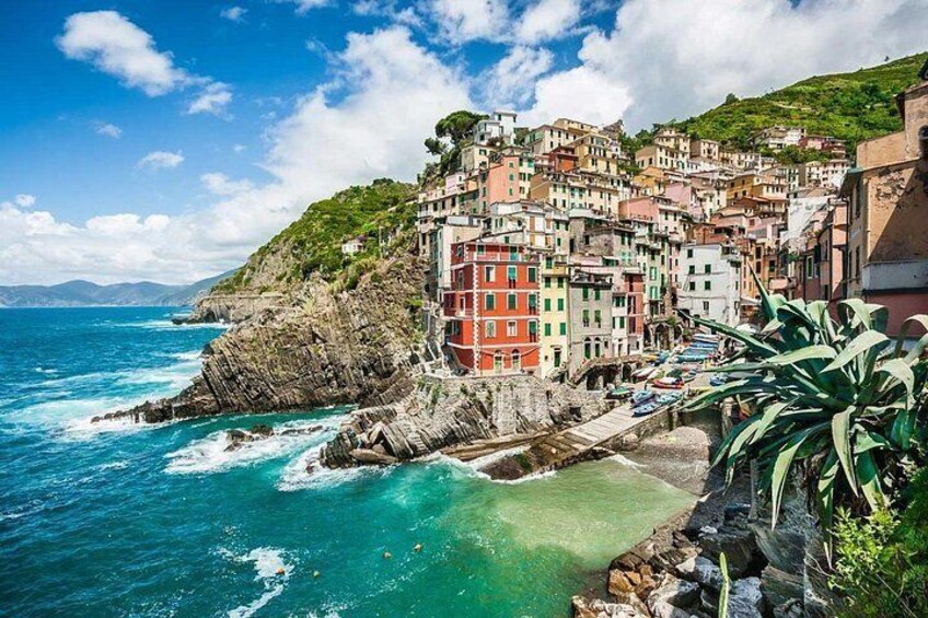 A coastal town with colorful buildings, a rocky shoreline, and a clear blue sky. 5