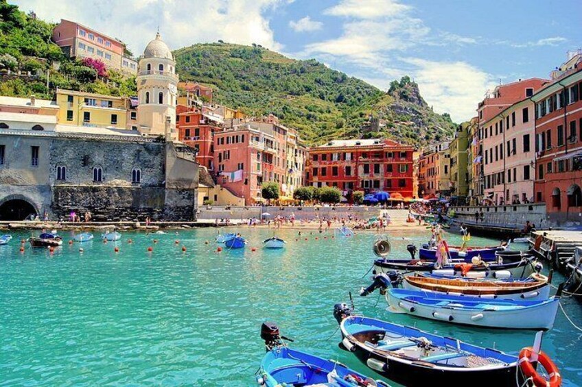 A coastal town with boats docked, historic buildings, and a clear blue sea. 3