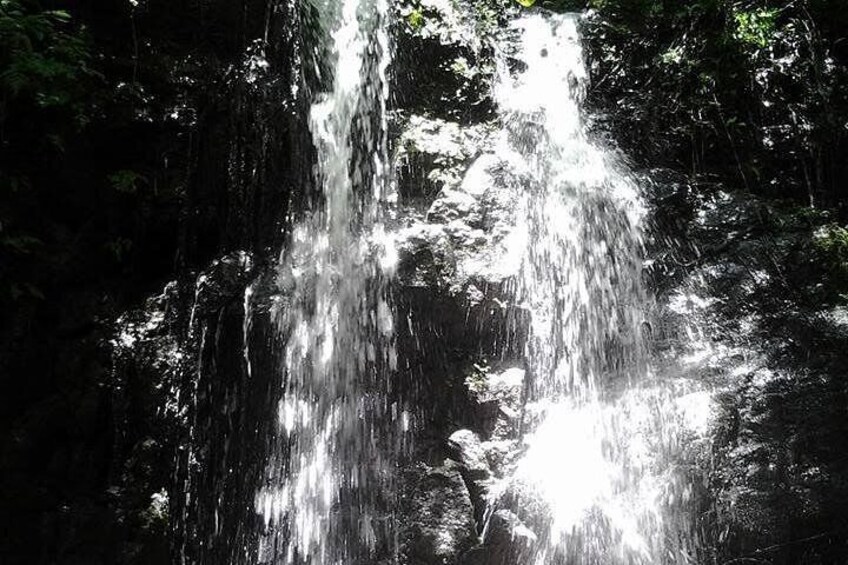 A waterfall cascading over rocks in a forested area. 5