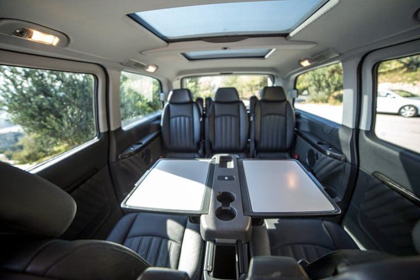 A vehicle interior with a table, seats, and a sunroof. 4