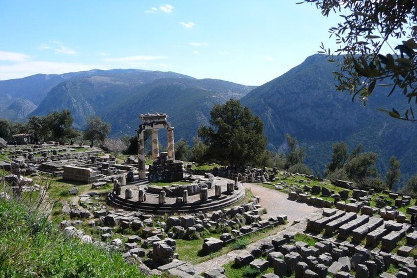 Ancient ruins with columns and stone structures, surrounded by mountains and greenery. 1