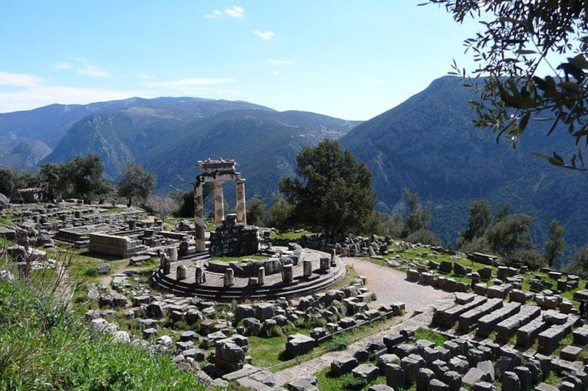 Ancient ruins with columns and stone structures, surrounded by mountains and greenery. 1