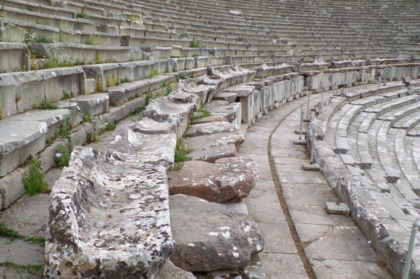 Un anfiteatro antiguo con asientos de piedra y un escenario central. 5