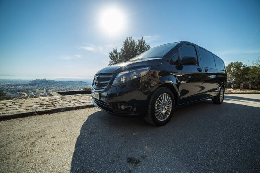 Una camioneta negra estacionada en una carretera con una vista panorámica de una ciudad y colinas al fondo. 2