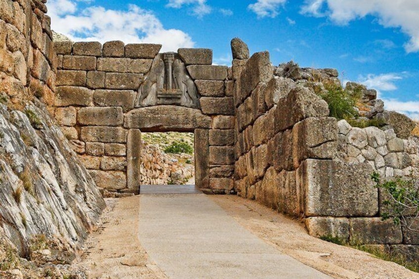 Un antiguo arco de piedra con un relieve escultórico, rodeado de muros de piedra y un sendero empedrado. 1