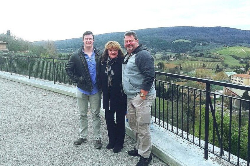 Drei Personen stehen auf einem Balkon mit Blick auf eine hügelige Landschaft. 4