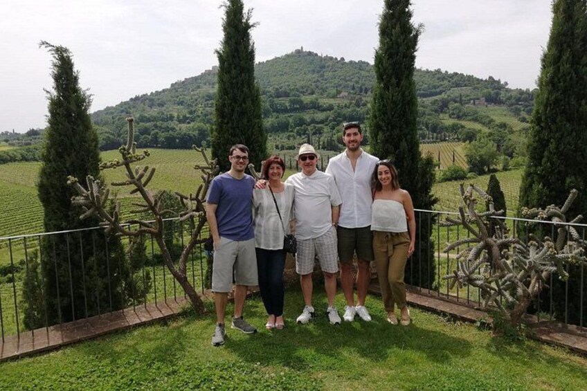 Un grupo de personas de pie en un área verde, con cipreses y un paisaje montañoso al fondo. 5
